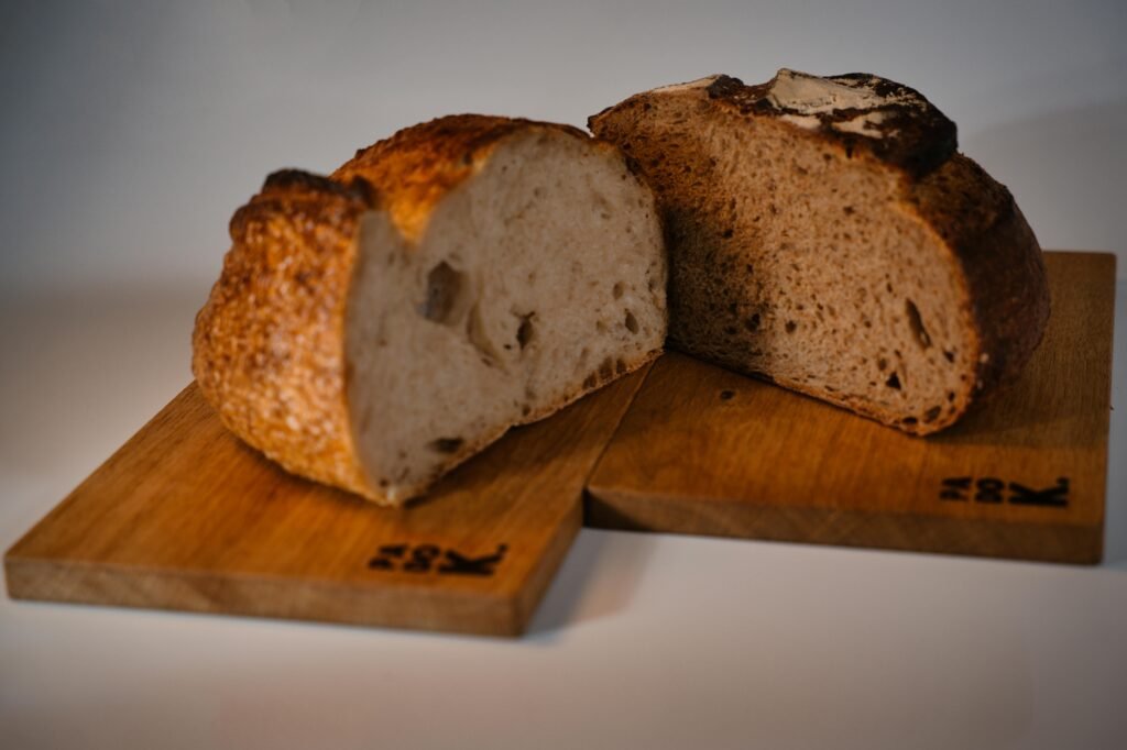 Close-up of artisanal bread loaves cut in half on wooden boards, showcasing texture.