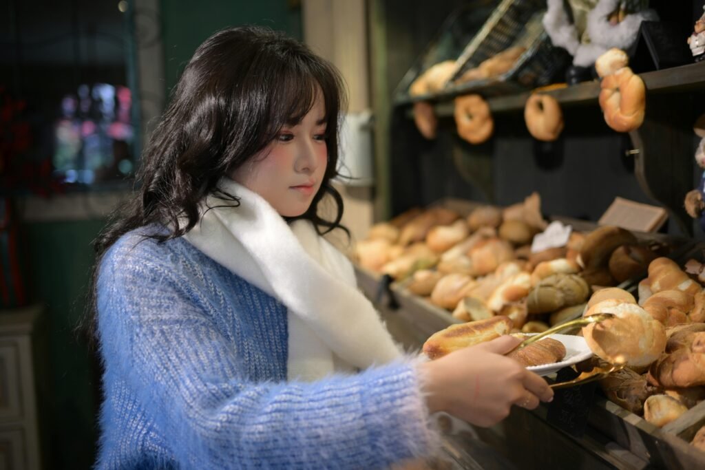 A woman in a bakery selecting fresh bread, showcasing a cozy indoor scene.