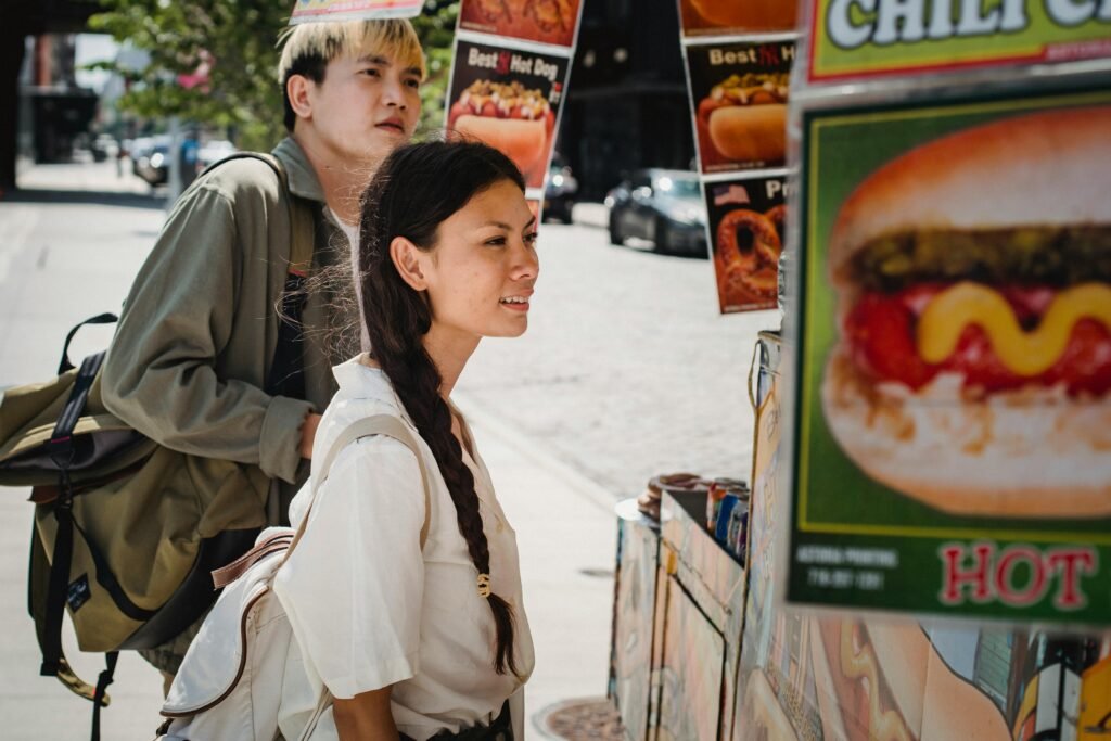 El sin gluten también se mueve por la calle A young couple looks at a street food stand on a sunny day in an urban setting, enjoying a carefree moment together.