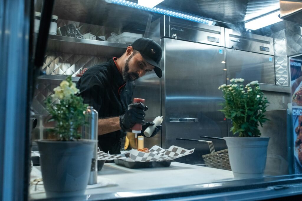 El sin gluten también se mueve por la calle A chef skillfully prepares a meal inside a food truck kitchen, showcasing culinary expertise.