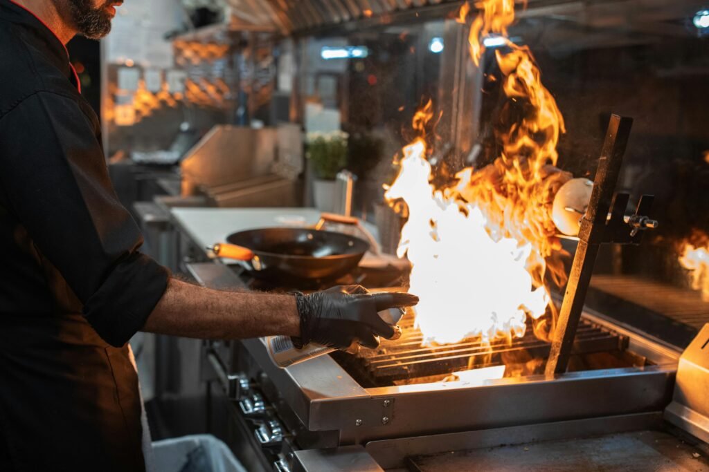 El sin gluten también se mueve por la calle A chef expertly grills meat on an open flame in a professional kitchen setting.