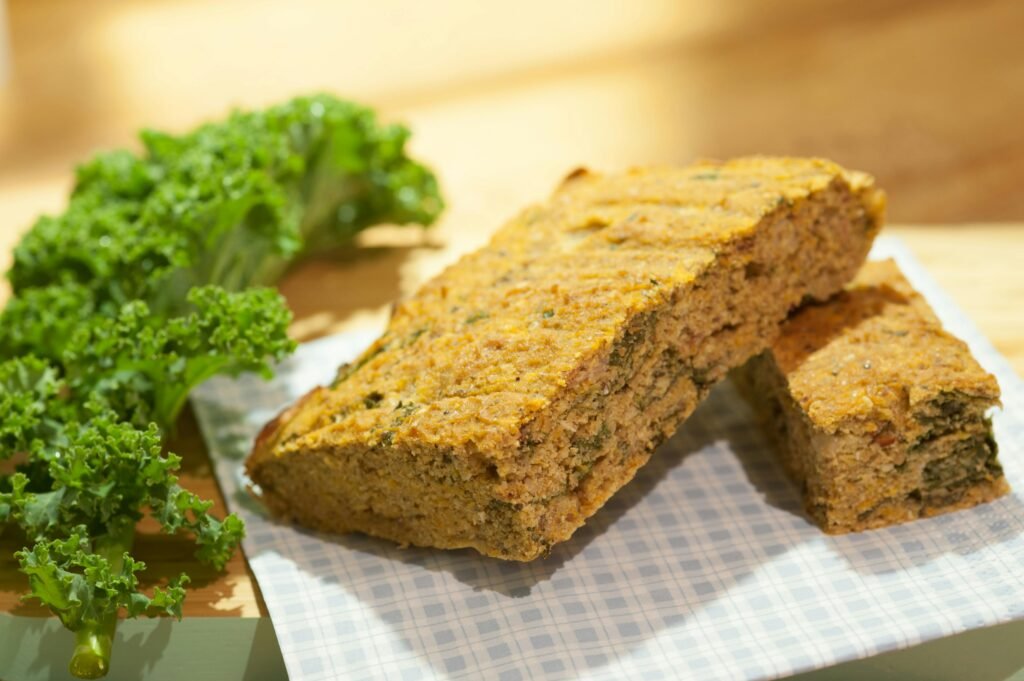 Alimentarse sin gluten cada día de forma saludable Close-up of freshly baked kale bread on a checkered napkin with fresh kale leaves.