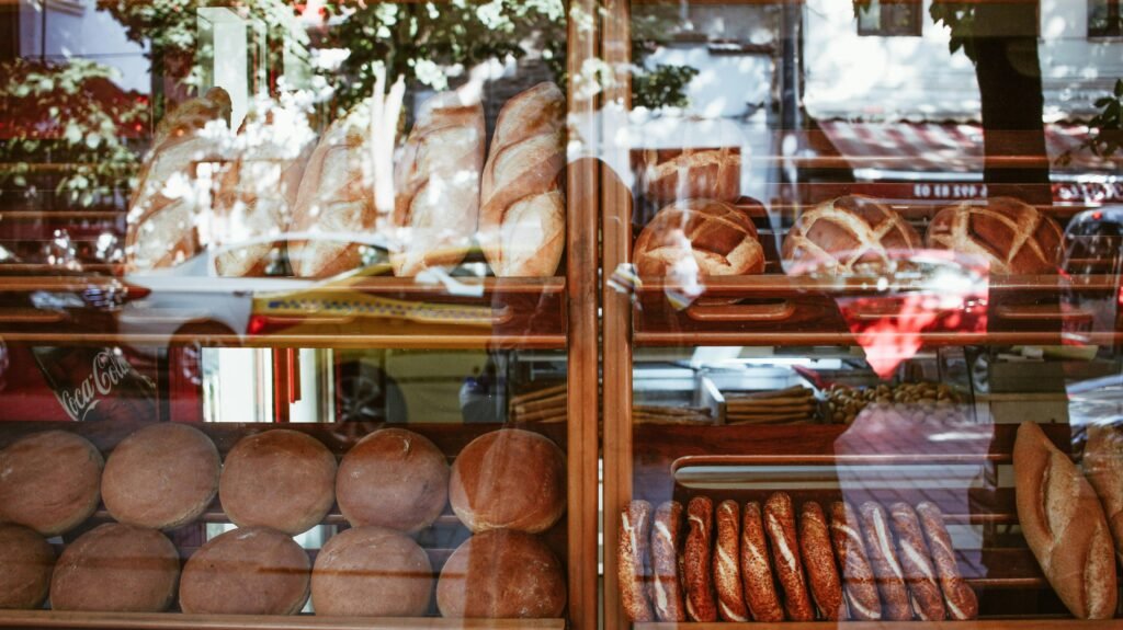 Freshly baked artisanal breads displayed in a bakery window showcasing a variety of loaves.